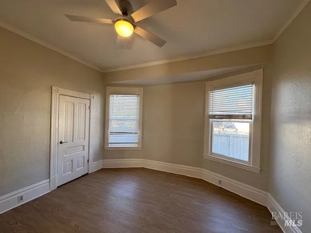 an empty room with wooden floor closet and windows