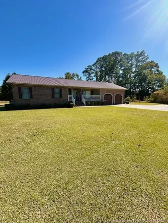 a front view of house with yard and trees in the background