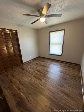 an empty room with wooden floor fan and windows