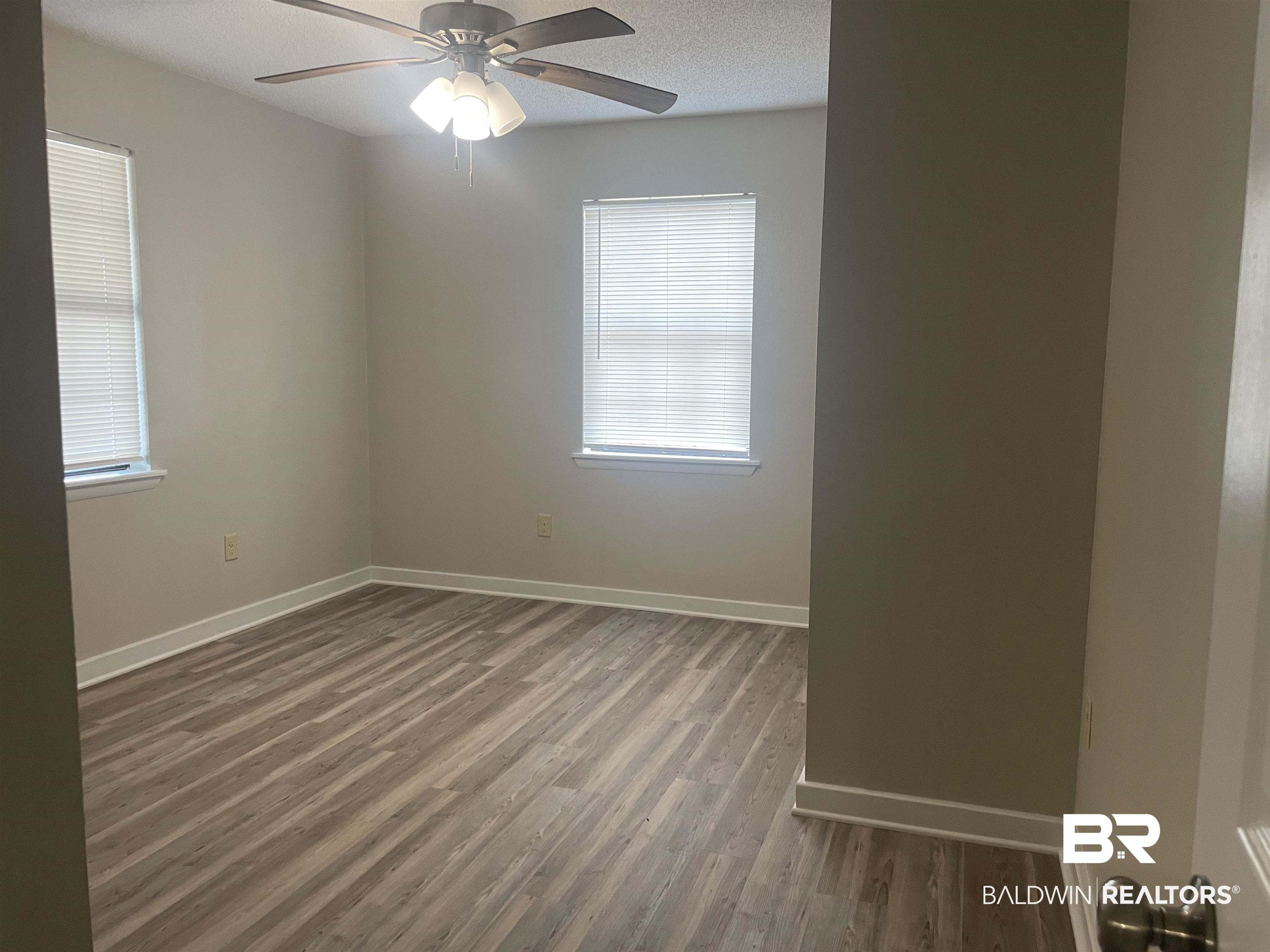 28414 Highway 31 Flomaton, AL 36441 - Photo 8 of 11 Unfurnished room with a healthy amount of sunlight, wood finished floors, baseboards, and a textured ceiling