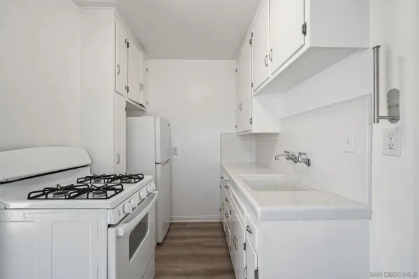 a kitchen view with wooden floor and white appliances