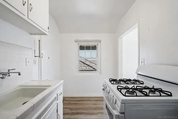 an empty room with a chandelier fan and windows