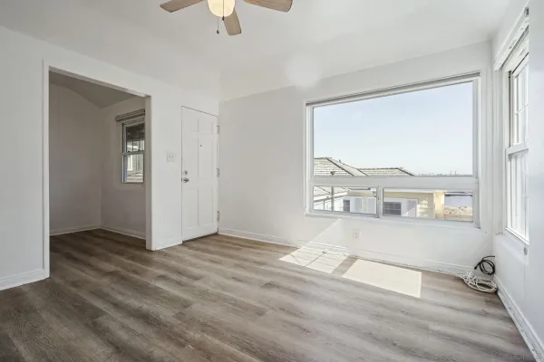 an empty room with wooden floor and windows