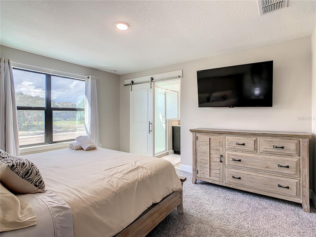 208 Villa Domani Circle Davenport, FL 33896 - Photo 17 of 26 a bedroom with a bed a flat screen tv and a window