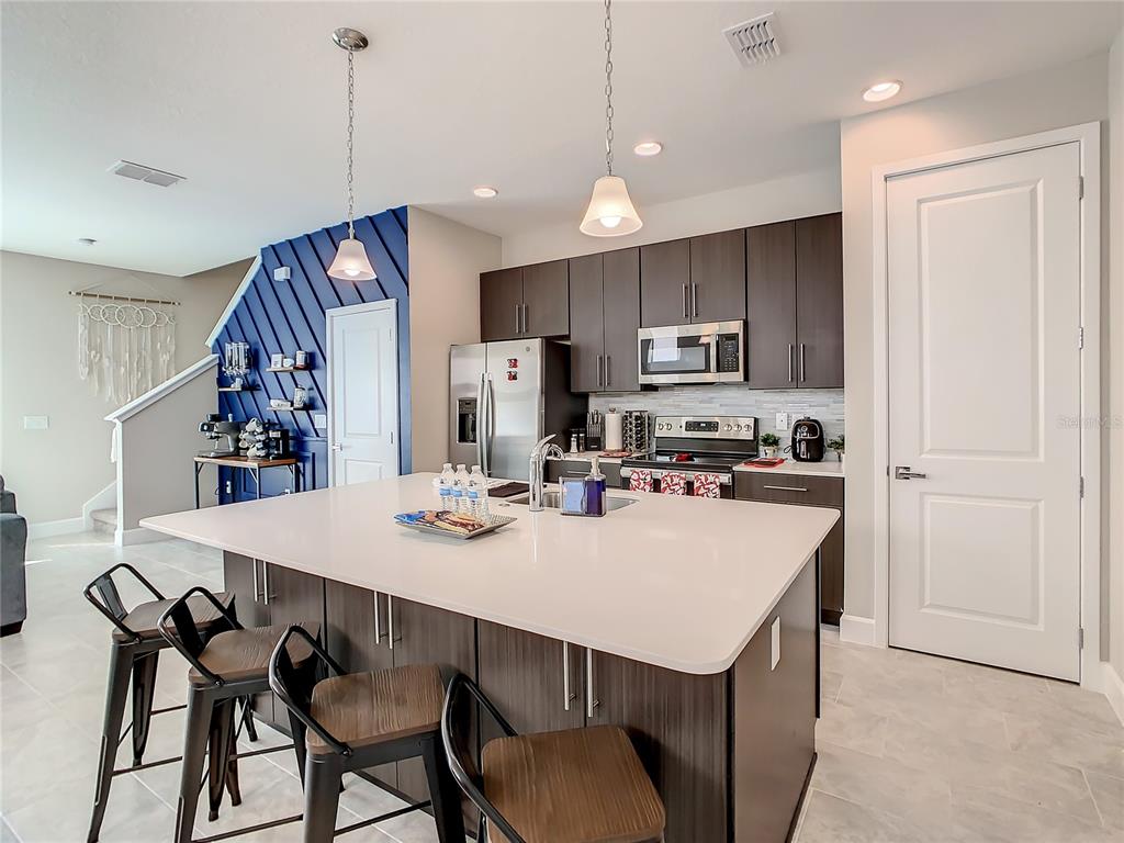 208 Villa Domani Circle Davenport, FL 33896 - Photo 4 of 26 a kitchen with a dining table chairs refrigerator and microwave