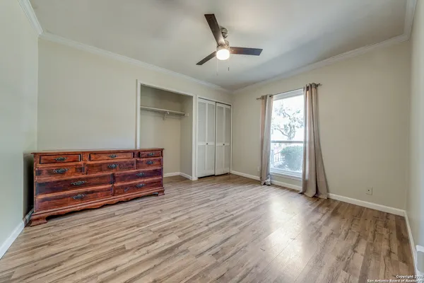 a view of empty room with wooden floor and fan