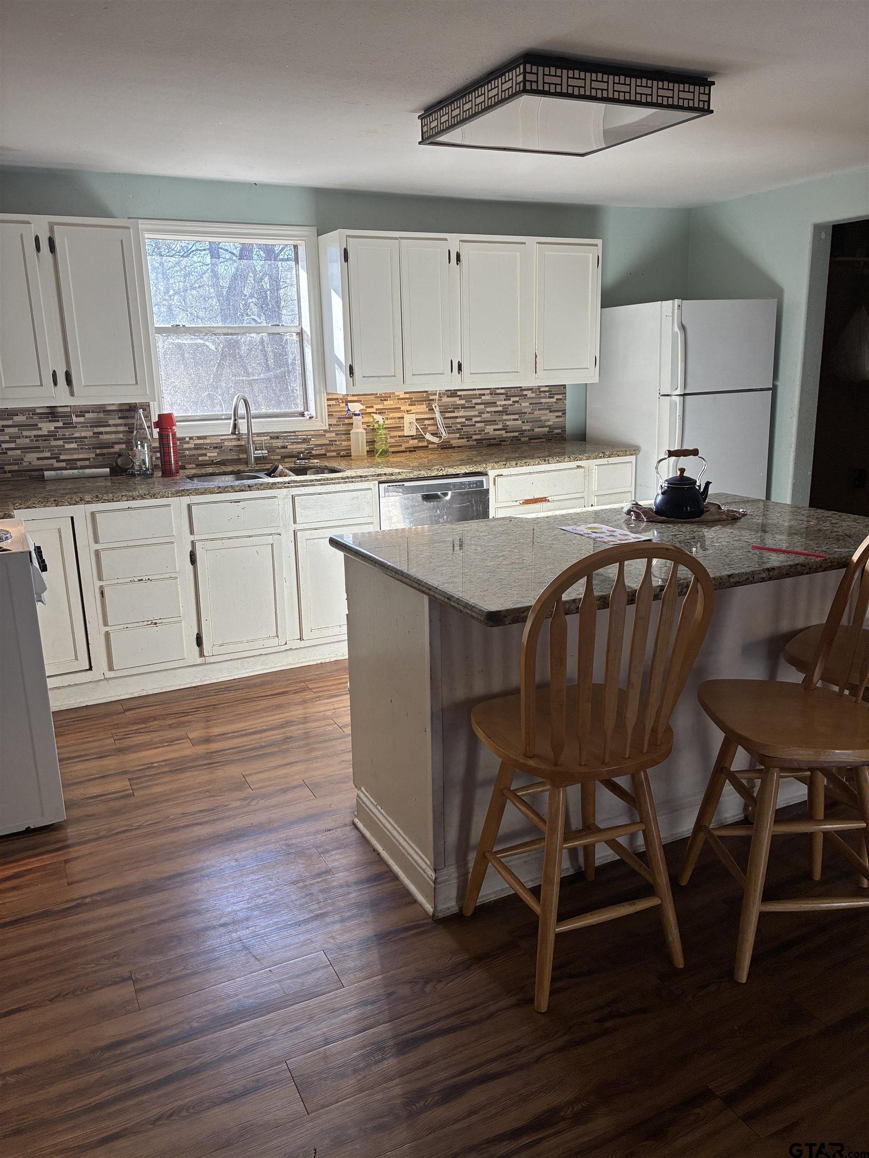 20519 Highway 69 Rusk, TX 75785 - Photo 15 of 20 a kitchen with granite countertop wooden floors cabinets and dining table chairs