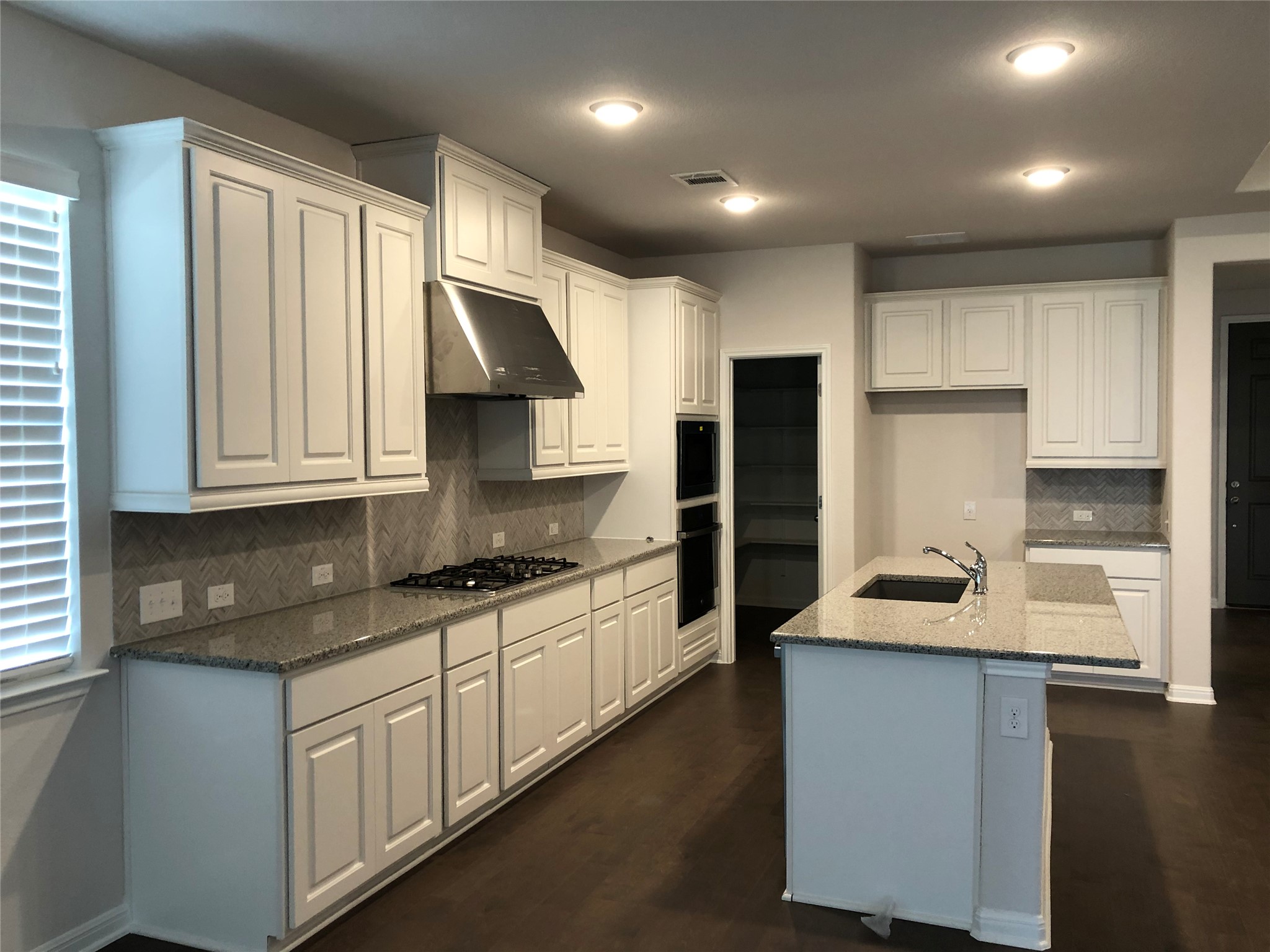 2746 Fortezza Way Round Rock, TX 78665 - Photo 5 of 16 Polished granite countertops complement classic white cabinetry and dark wood floors in this modern workspace.