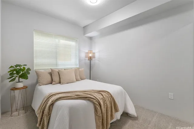 a bed sitting in a bedroom next to a window and a potted plant