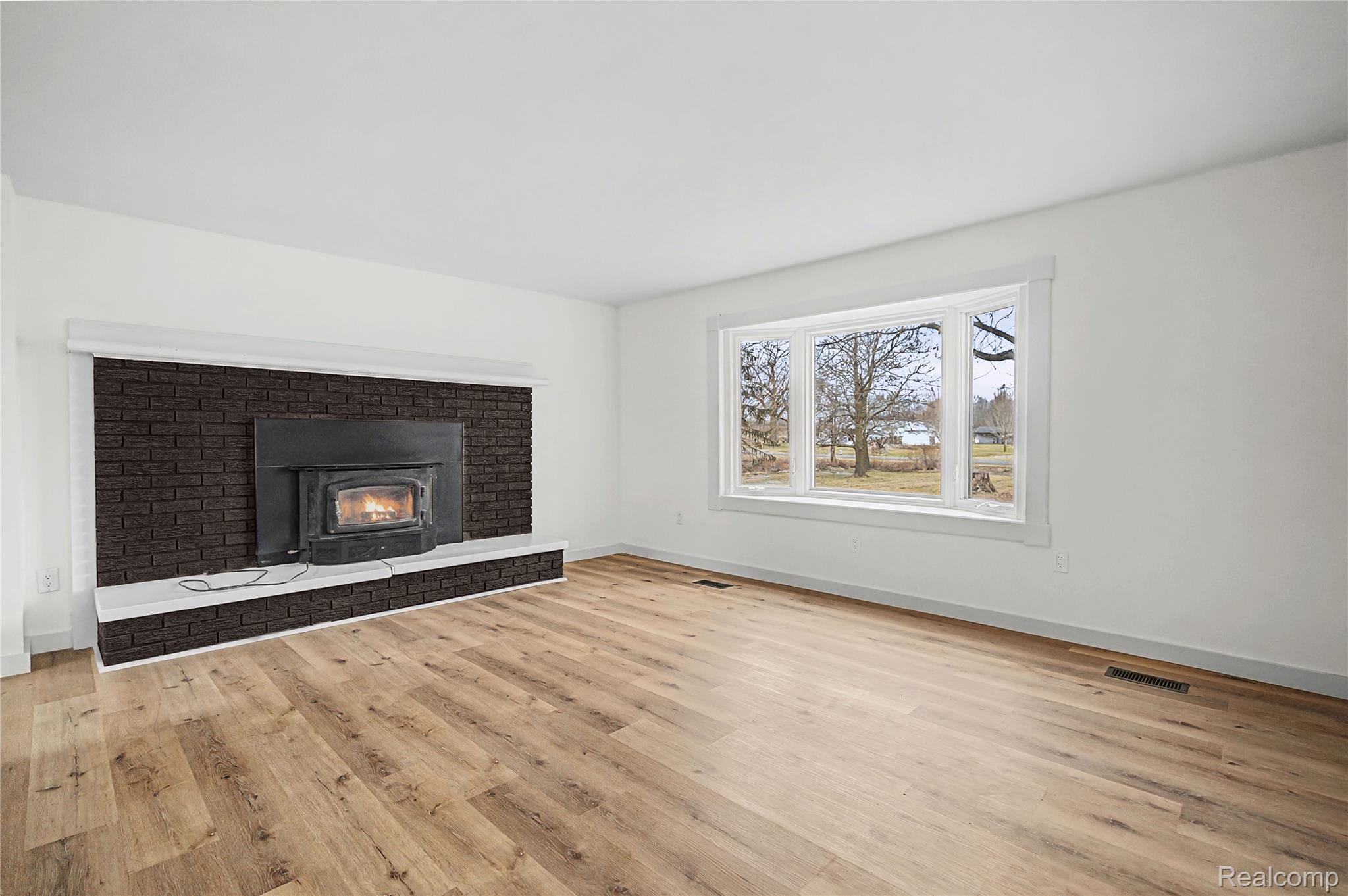 14308 North Belsay Road Millington, MI 48746 - Photo 28 of 51 Unfurnished living room with light wood-type flooring and a brick fireplace
