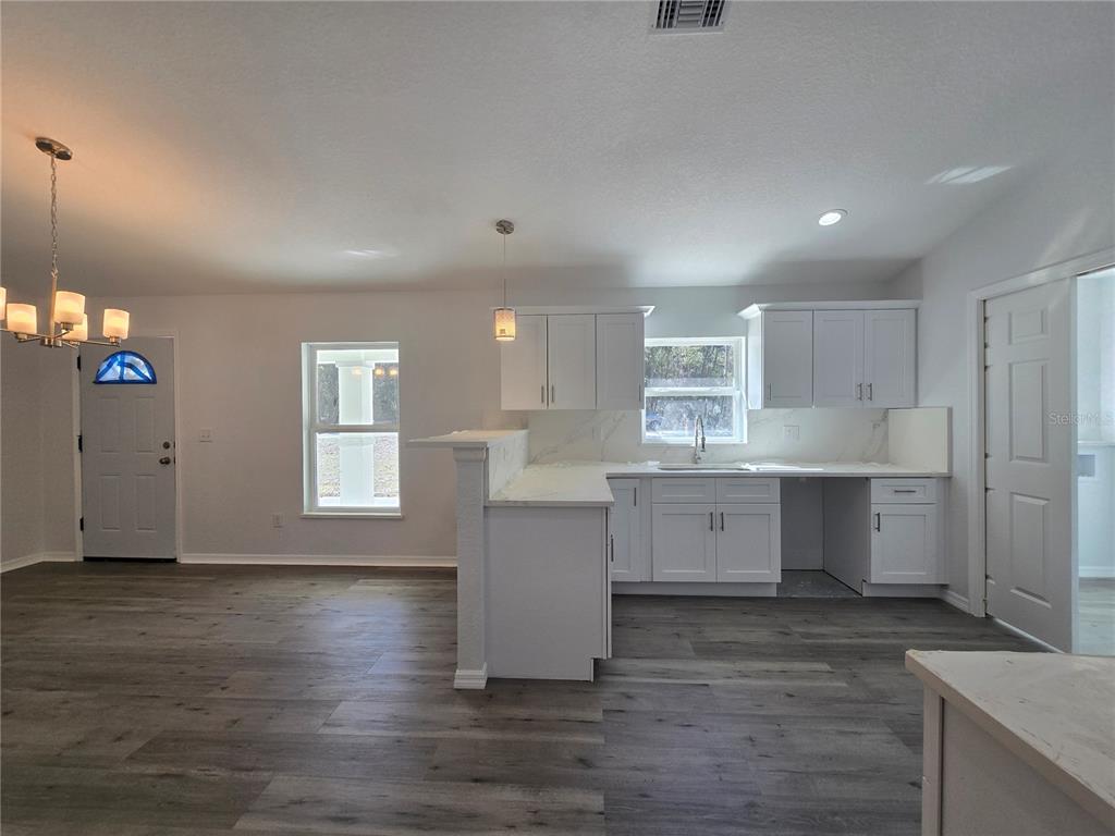 131 Fisher Road Ocklawaha, FL 32179 - Photo 25 of 41 a kitchen with wooden floors and white cabinets