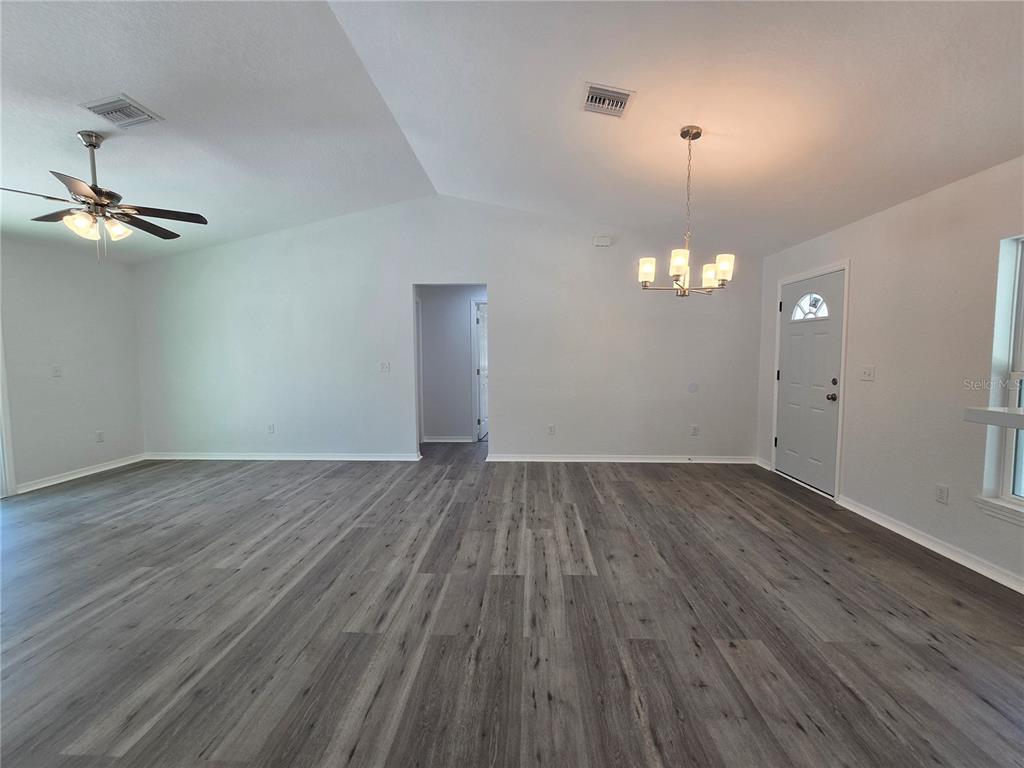 131 Fisher Road Ocklawaha, FL 32179 - Photo 29 of 42 an empty room with wooden floor chandelier fan and windows