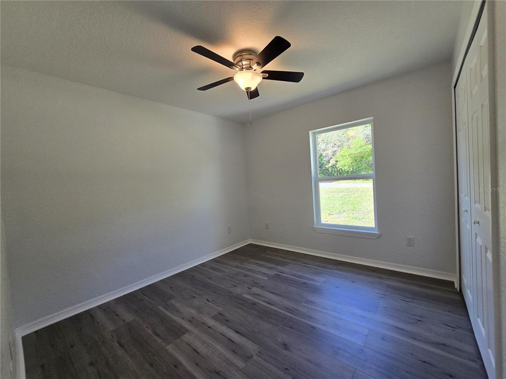 131 Fisher Road Ocklawaha, FL 32179 - Photo 31 of 42 an empty room with wooden floor fan and windows
