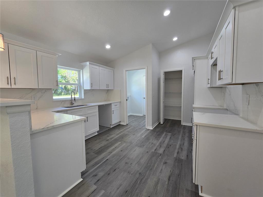 131 Fisher Road Ocklawaha, FL 32179 - Photo 38 of 42 a kitchen with wooden floors and cabinets