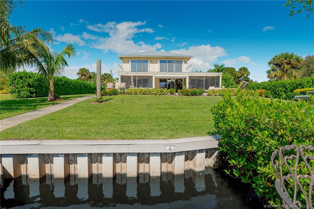 5854 Southeast Horseshoe Point Road Stuart, FL 34997 - Photo 52 of 56 a view of a white house in a big yard with table and chairs and palm trees