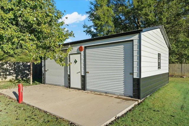a view of small white house with a small yard and large tree