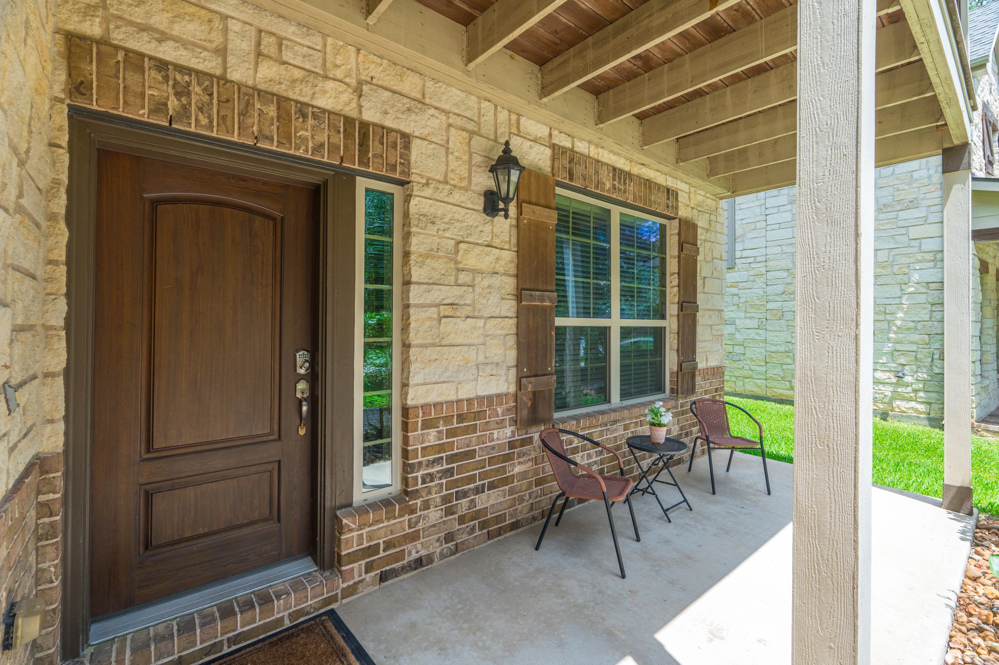 79 West Jagged Ridge Circle Spring, TX 77389 - Photo 7 of 50 Step up to this gorgeous covered entry featuring a rich dark wood front door framed by stone columns and warm sconce lighting. It's a welcoming first impression that sets the tone for the comfort and style waiting for you just beyond the threshold.