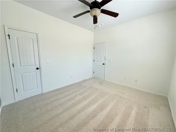 an empty room with windows and ceiling fan