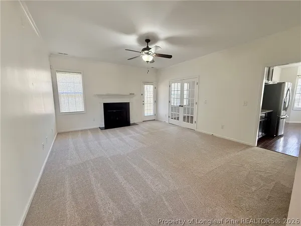 a view of a livingroom with a fireplace a ceiling fan and wooden floor