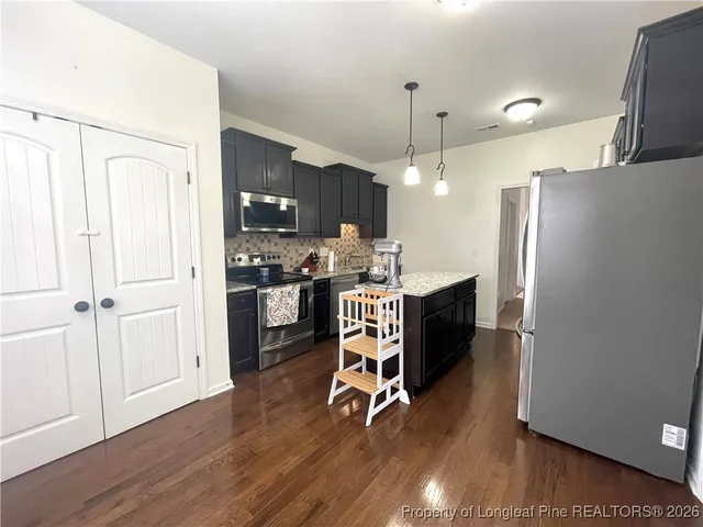 a room with stainless steel appliances a refrigerator oven a sink dishwasher and a stove with wooden floor