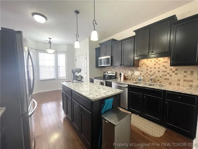 a kitchen with granite countertop stainless steel appliances a sink stove and refrigerator