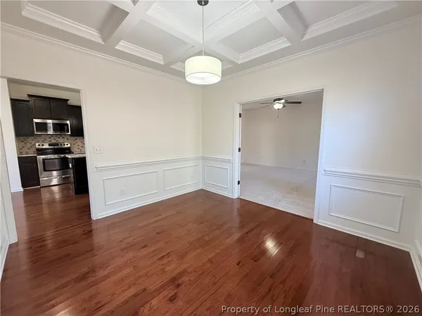 an empty room with wooden floor staircase and windows