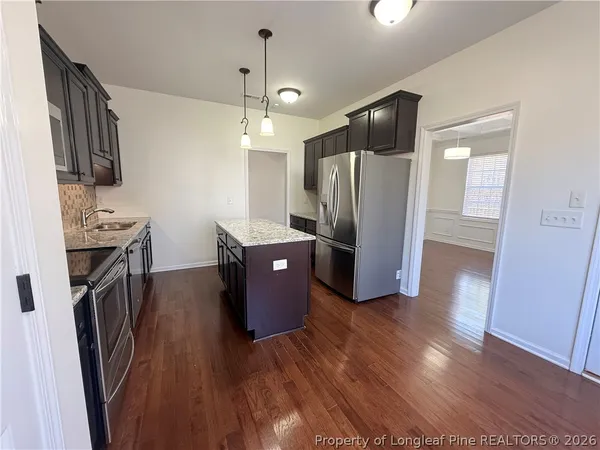 a view of kitchen with stainless steel appliances refrigerator stove microwave and cabinets