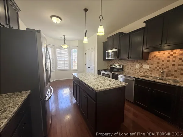 a kitchen with stainless steel appliances granite countertop wooden cabinets a stove top oven a sink and dishwasher