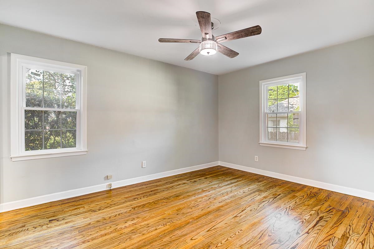 5676 Barfield Road Memphis, TN 38120 - Photo 17 of 19 Bright room featuring wood-finish flooring, light gray wall paint, white trim, and a ceiling fan with integrated lighting