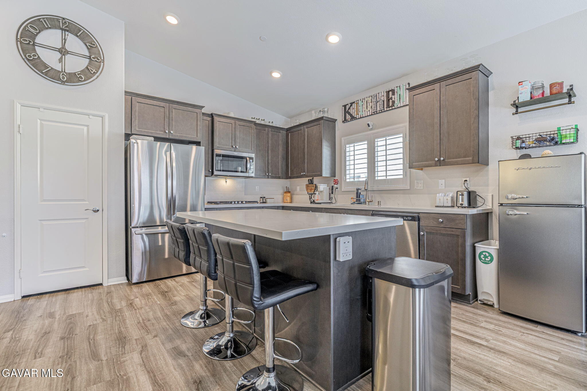 44302 Marbella Street Lancaster, CA 93536 - Photo 4 of 38 a kitchen with kitchen island a stove a refrigerator and a dining table with wooden floor
