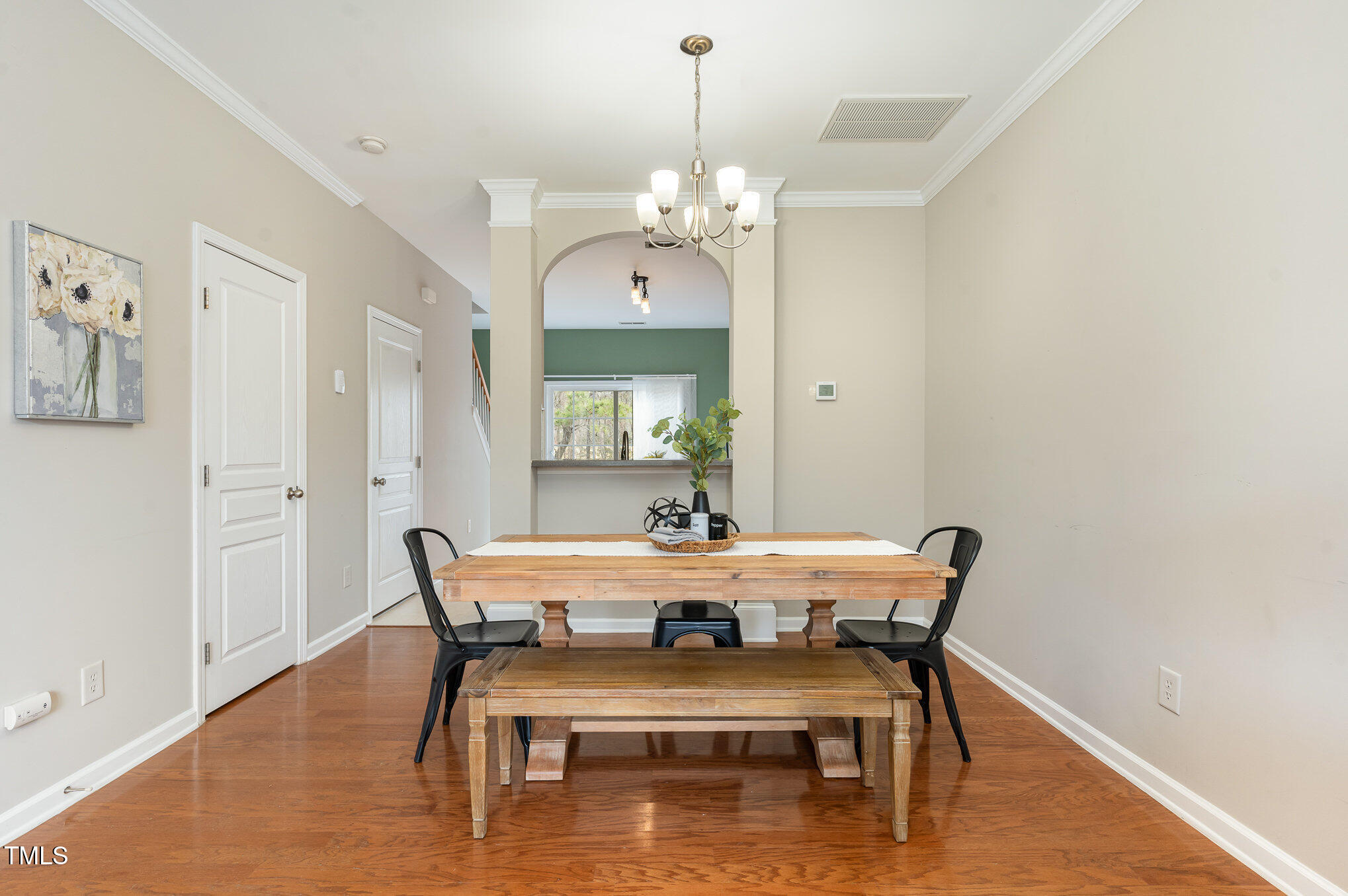 7810 Spungold Street Raleigh, NC 27617 - Photo 3 of 12 a dining room with wooden floor a chandelier a wooden table and chairs