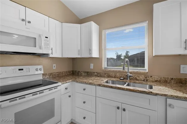 a kitchen with granite countertop white cabinets and white appliances