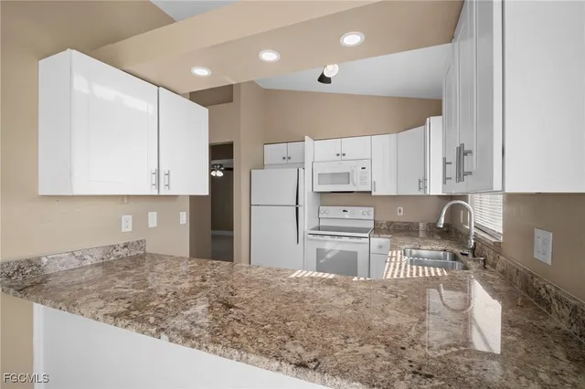 a kitchen with stainless steel appliances granite countertop a sink refrigerator and cabinets