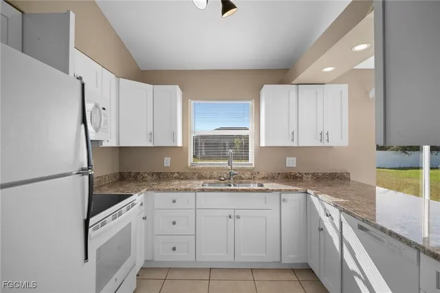 a kitchen with a sink dishwasher a white stove refrigerator and white cabinets with wooden floor