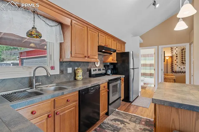 a kitchen with stainless steel appliances granite countertop a sink stove refrigerator and cabinets