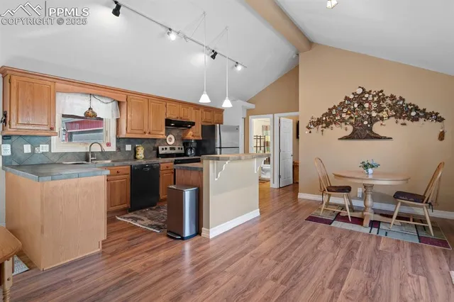 a kitchen with stainless steel appliances a microwave a stove a sink dishwasher a refrigerator white cabinets with wooden floor