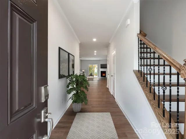a hallway with wooden floor stairs and a potted plant