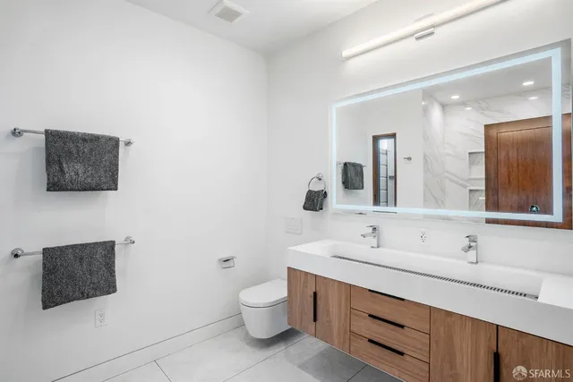 a bathroom with a double vanity sink mirror and toilet