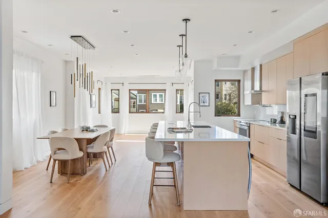 a dining room with stainless steel appliances kitchen island granite countertop a dining table chairs and a refrigerator