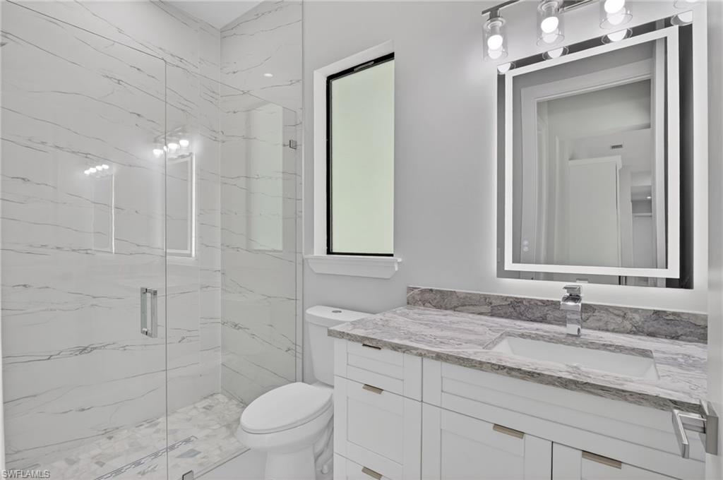 563 15th Street Northwest Naples, FL 34120 - Photo 11 of 22 a bathroom with a granite countertop sink a toilet and a mirror