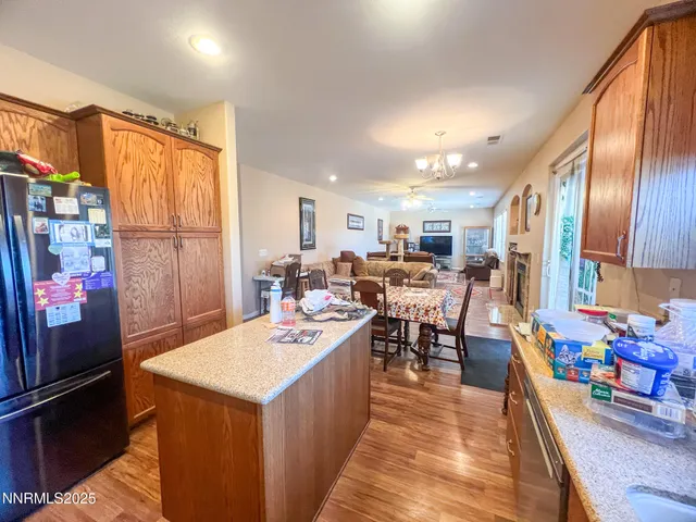 a open kitchen with stainless steel appliances kitchen island granite countertop a refrigerator a stove a sink dishwasher with a dining table and chairs with wooden floor