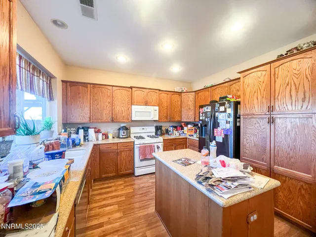 a kitchen with stainless steel appliances kitchen island granite countertop a stove refrigerator and cabinets