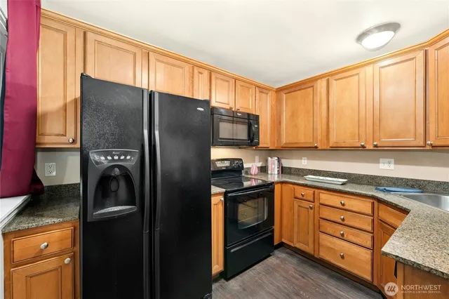 a kitchen with stainless steel appliances granite countertop a sink a stove cabinets and wooden floor