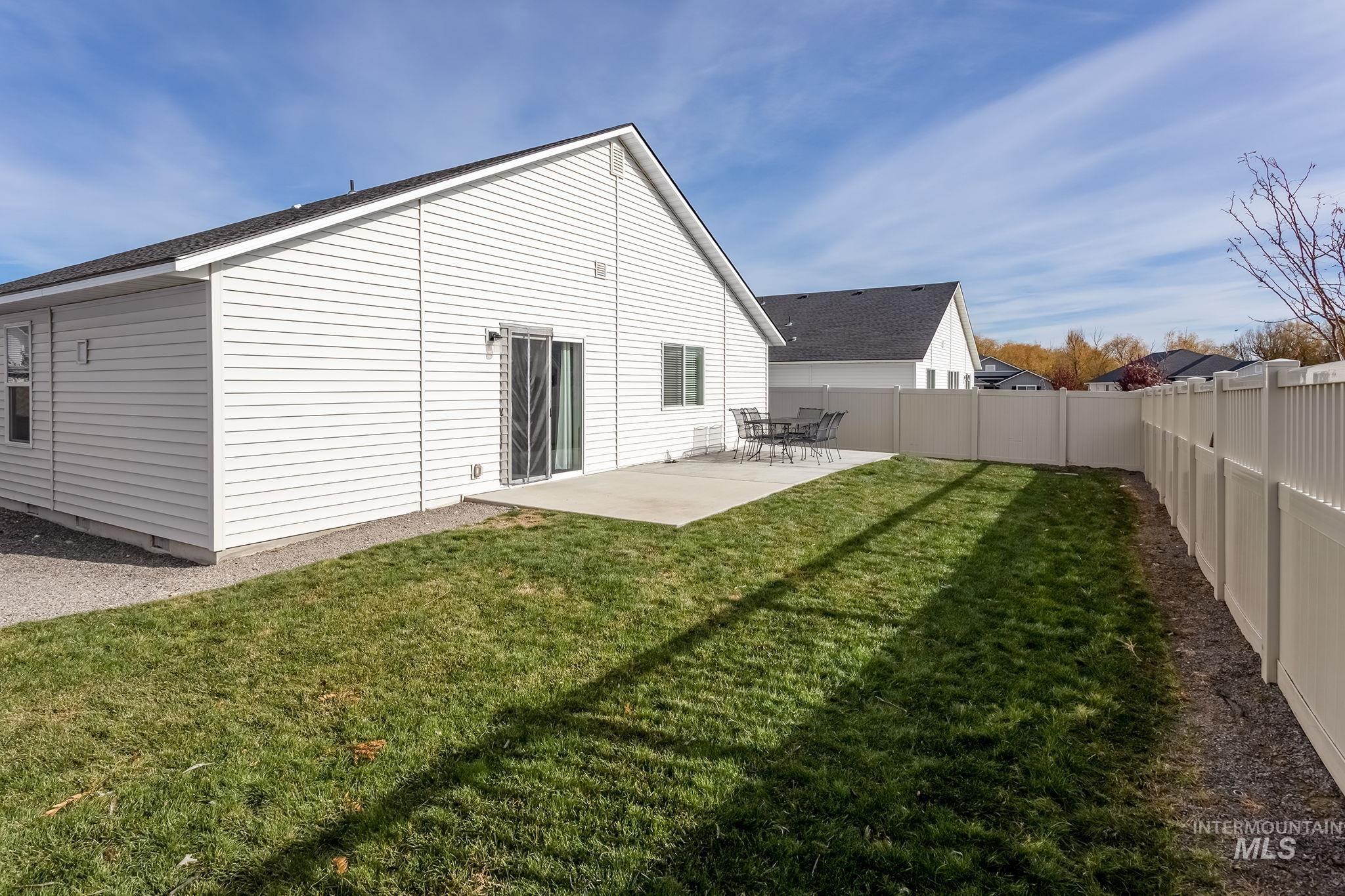 12771 Carkhill Street Caldwell, ID 83607 - Photo 13 of 13 Private backyard featuring a concrete patio, sliding glass door access, and a full-height vinyl privacy fence