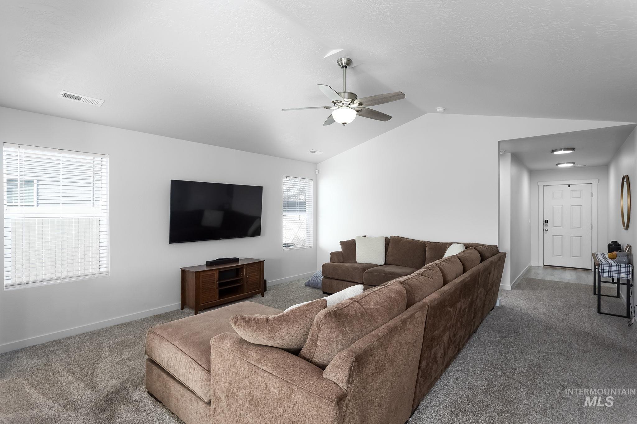 12771 Carkhill Street Caldwell, ID 83607 - Photo 4 of 13 Spacious living area featuring vaulted ceilings, a ceiling fan with integrated lighting, and neutral carpeting