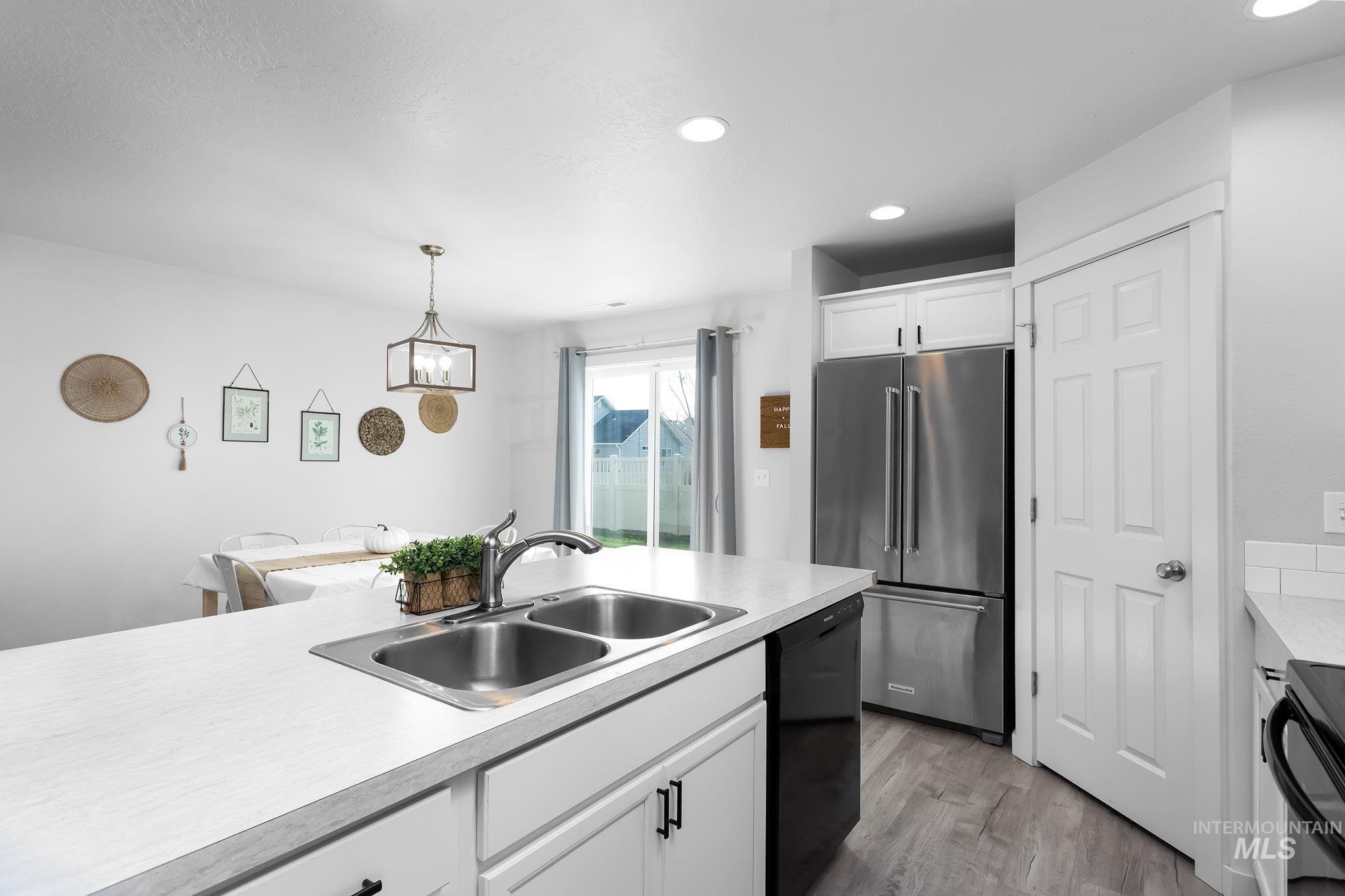 12771 Carkhill Street Caldwell, ID 83607 - Photo 8 of 13 Modern kitchen featuring a double basin stainless steel sink, white countertops, and white cabinetry with matte black hardware