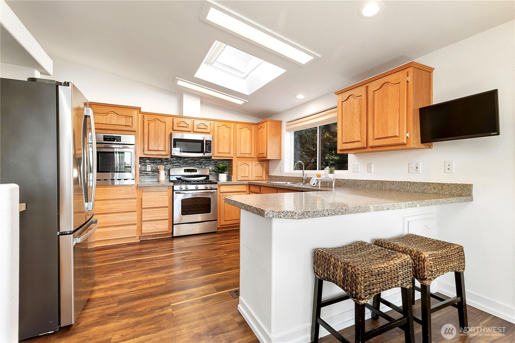 3834 South Passage View Lane Langley, WA 98260 - Photo 18 of 40 a kitchen with stainless steel appliances granite countertop a stove top oven a sink dishwasher a dining table and chairs with wooden floor