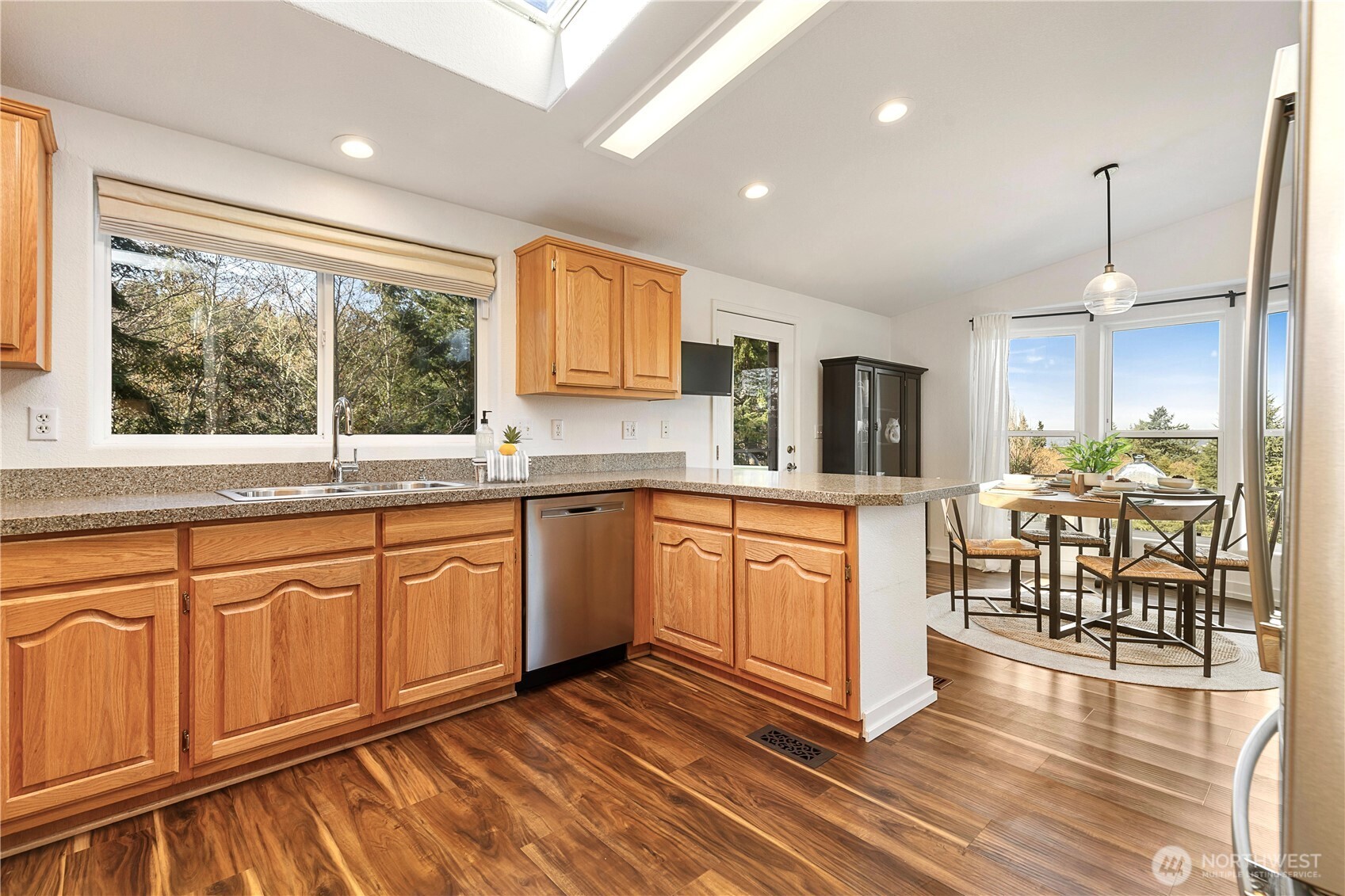 3834 South Passage View Lane Langley, WA 98260 - Photo 22 of 40 a large kitchen with stainless steel appliances granite countertop a stove a sink dishwasher a dining table and chairs with wooden floor