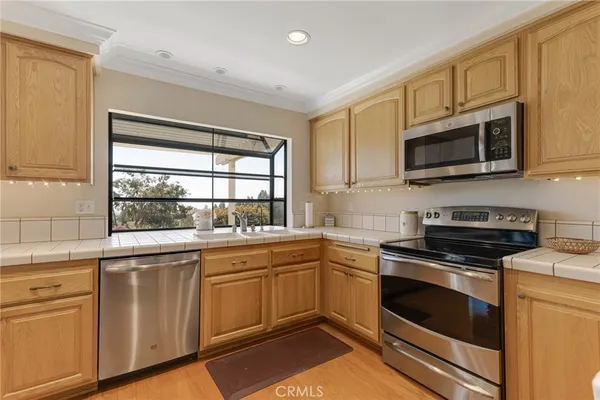 a kitchen with cabinets stainless steel appliances a sink and a window