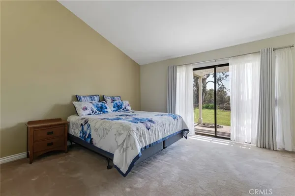 a spacious bedroom with a bed and a dresser next to a window